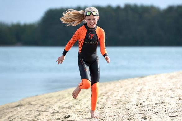 meisje-rennend-in-schoolslag-wetsuit-op-strand.jpg